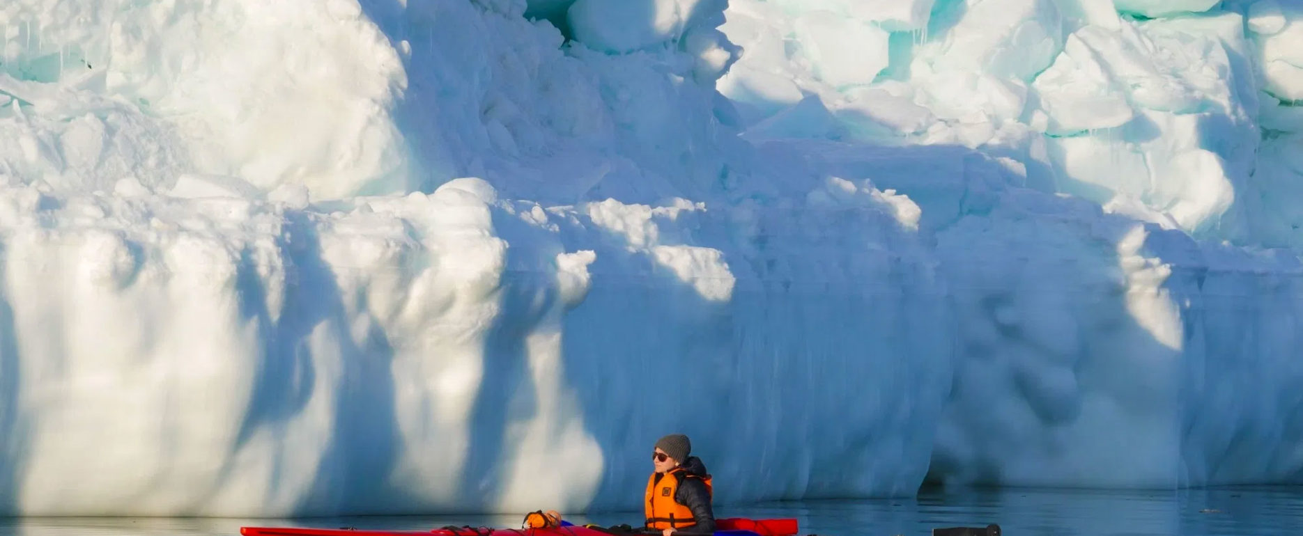 Guide Jody Steeves slips through the calm waters of Hudson Bay in a kayak on Churchill Wild's Journey to the Floe Edge safari