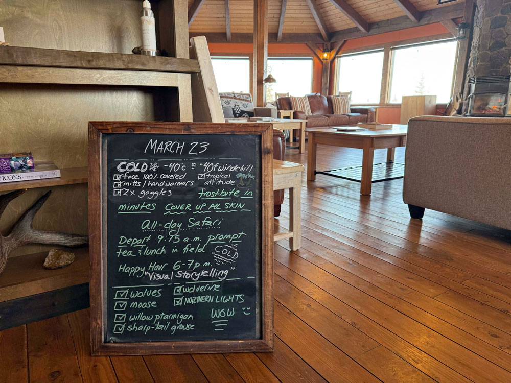The Daily Briefing Board at Churchill Wild's Nanuk Polar Bear Lodge, with the glowing fireplace and snow outside the windows. Cloud Wolves of the Kaska Coast safari. Ellen Zangla photo
