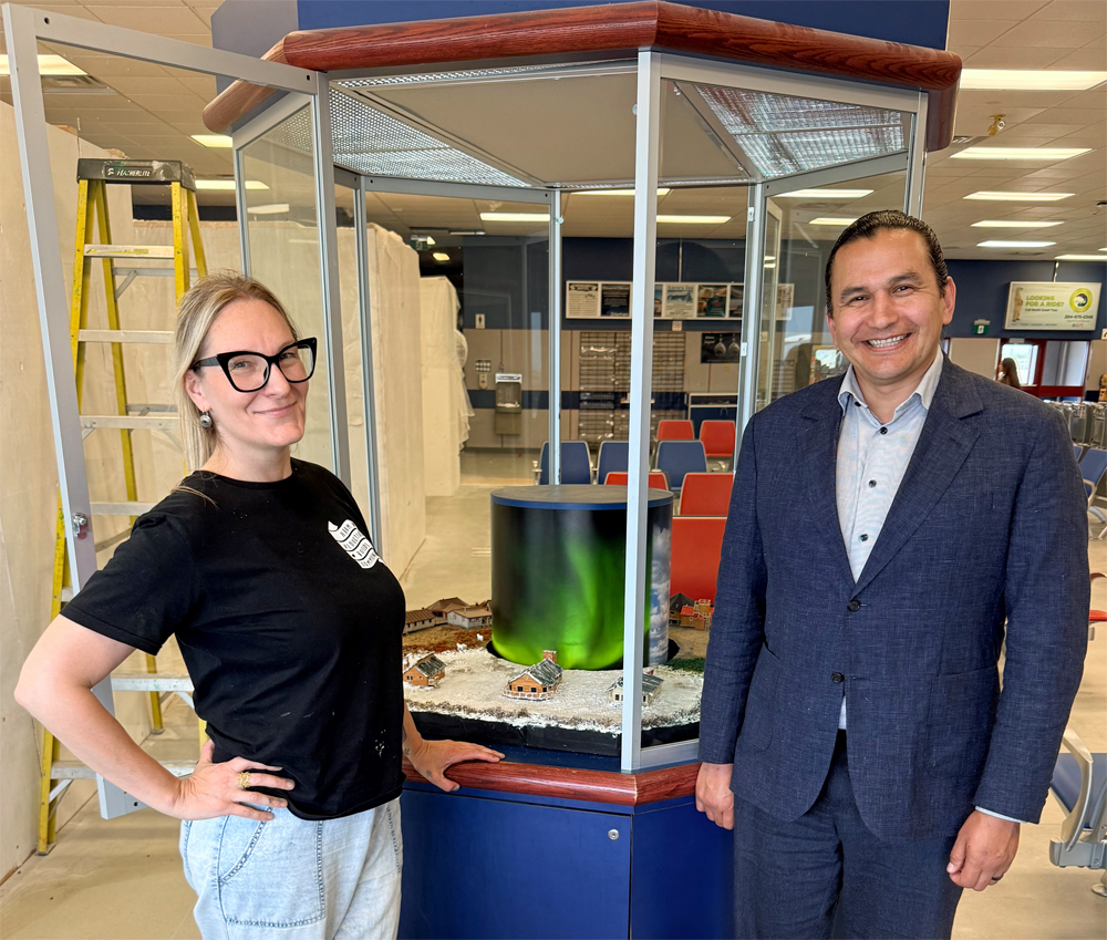 Churchill Wild diorama creator Jen Arnold and Manitoba Premier Wab Kinew in front of Jen's new creation at the Churchill airport.